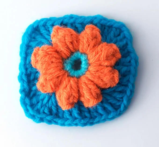 Crochet orange flower on blue granny square