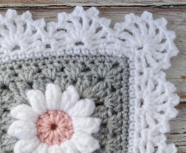 Gray crochet afghan with white flowers and white border