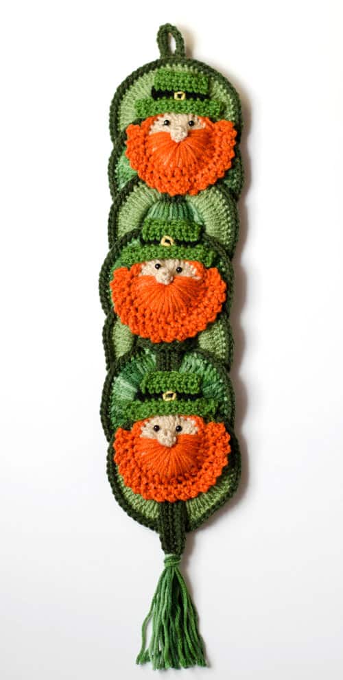 Crochet leprechauns on a wallhanging in green and orange