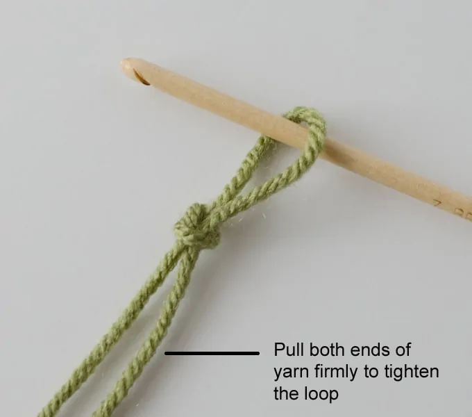 green yarn and wood hook making slip stitch loop