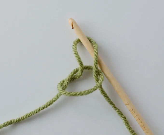 Slip stitch with green yarn and a wooden crochet hook.