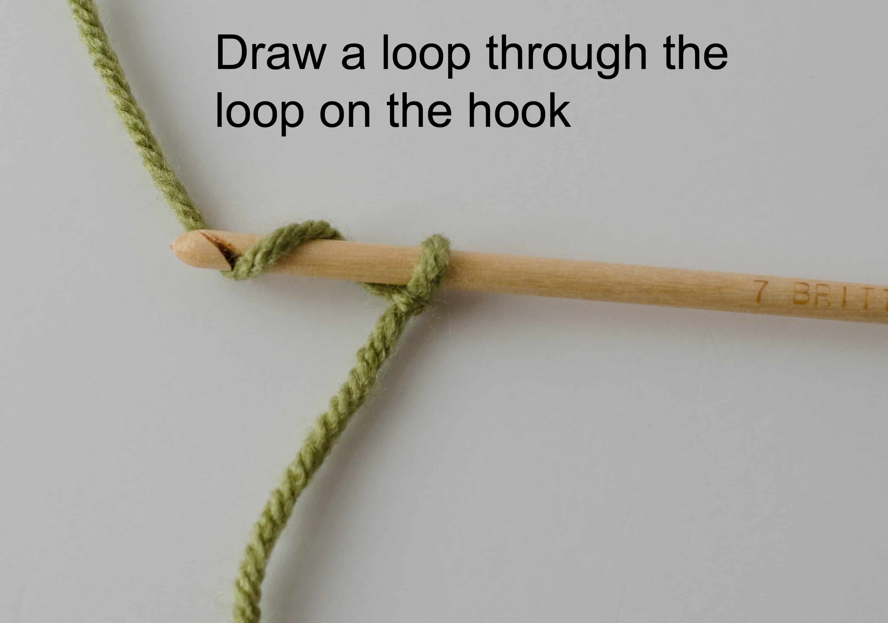 green yarn and wood hook making slip stitch loop