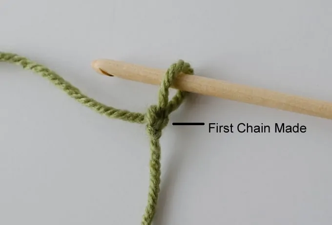 green yarn and wood hook making slip stitch loop