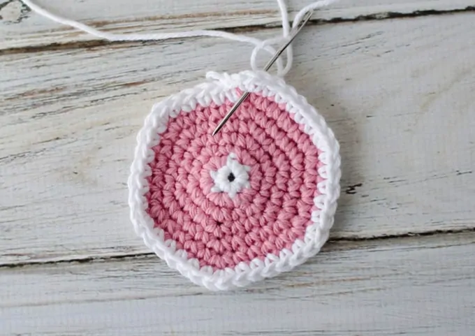 Crochet coaster pattern in progress with yarn needle
