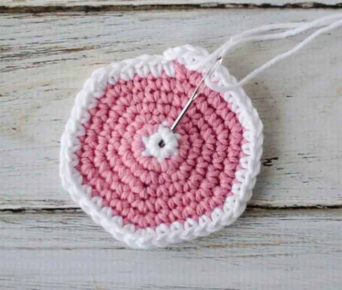 Crochet coaster pattern in progress with yarn needle