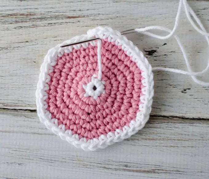 Crochet coaster pattern in progress with yarn needle