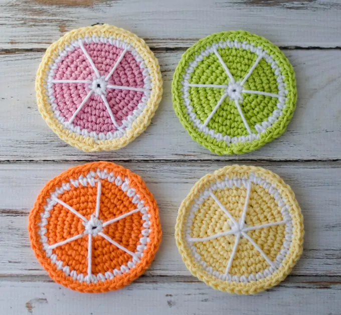 Four Crochet Citrus coasters in yellow, green, orange, pink and white 