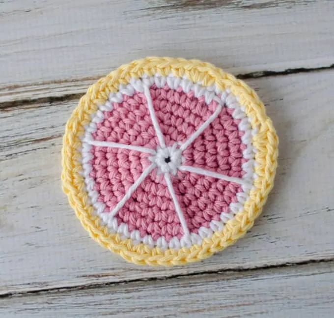 Crochet grapefruit coaster in pink, yellow and white