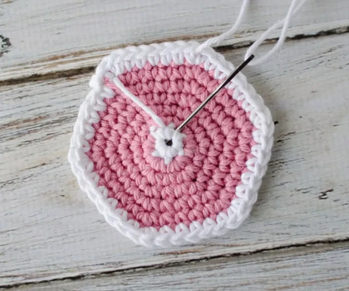 Crochet coaster pattern in progress with yarn needle