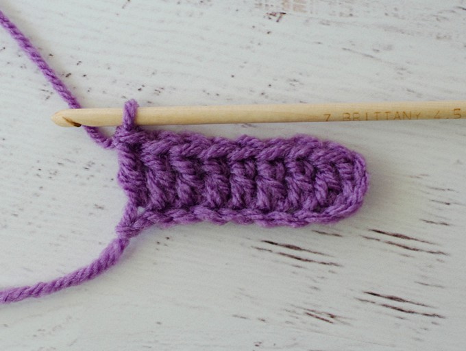 Row of purple double crochet stitches with wood hook