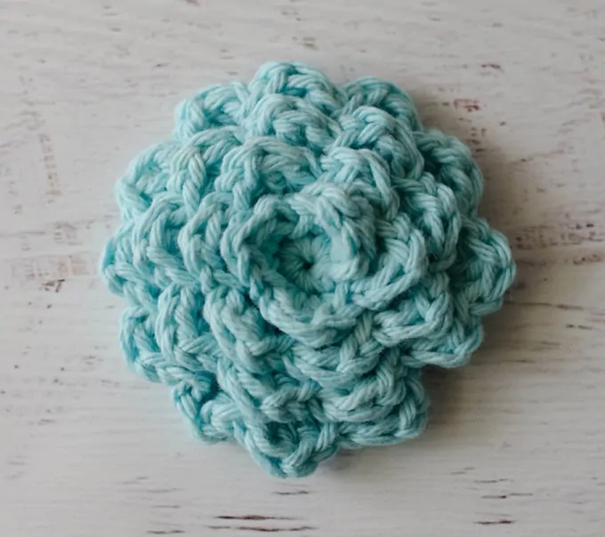A blue crochet ruffles face scrubbie.