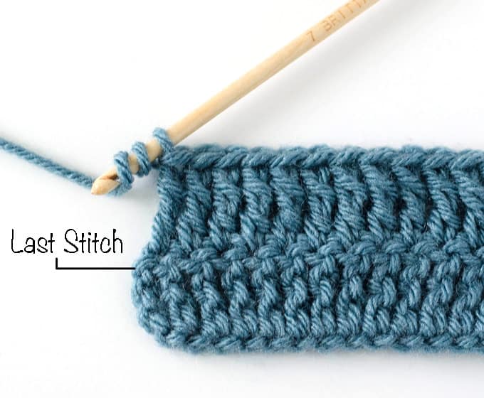 Crochet treble stitch in progress with blue yarn and wood hook