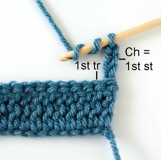 Crochet treble stitch in progress with blue yarn and wood hook