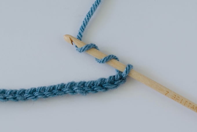 chain stitch in blue yarn with wood hook