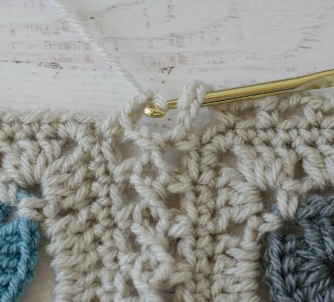 Crochet afghan squares in ivory being joined with flat braid join technique