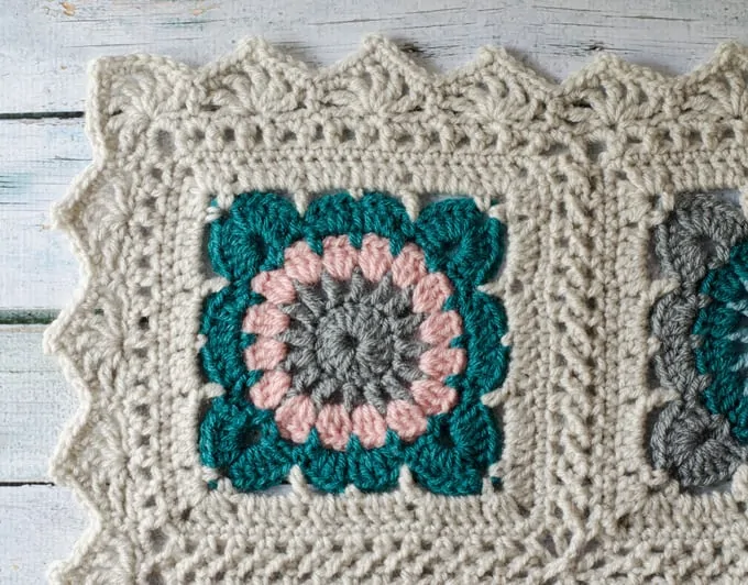 corner of crochet afghan in ivory, teal, pink and gray