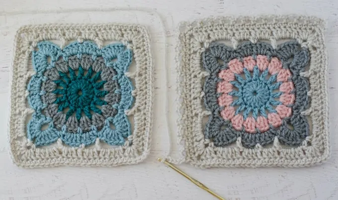 Two afghan squares in ivory, blue and pink yarn