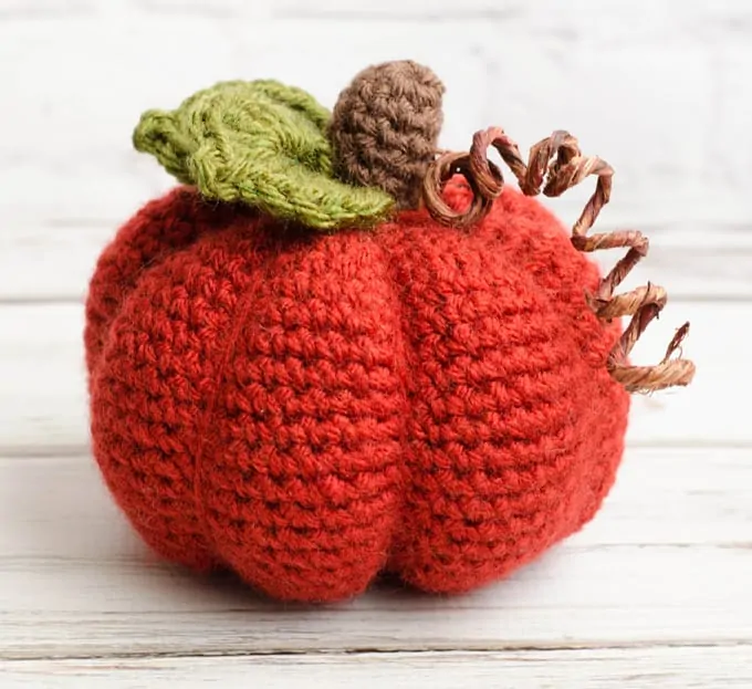 Orange crochet pumpkin with green leaves and brown stem