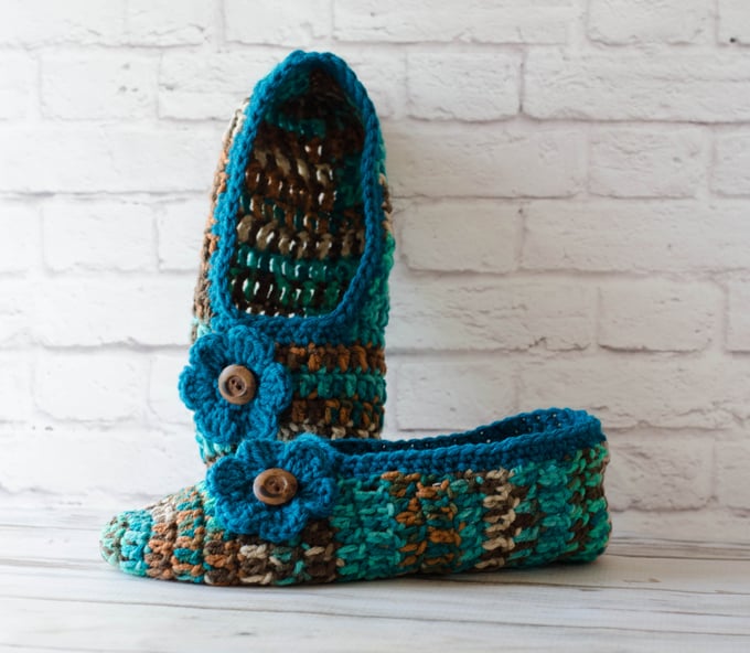 crochet slippers propped against a white brick wall