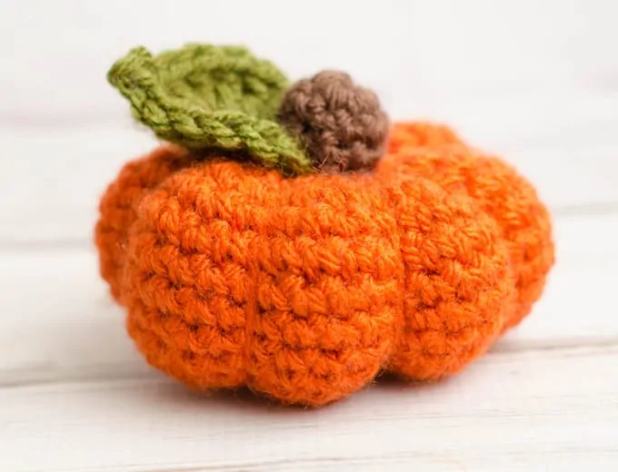 short orange crochet pumpkin with green leaf and brown stem
