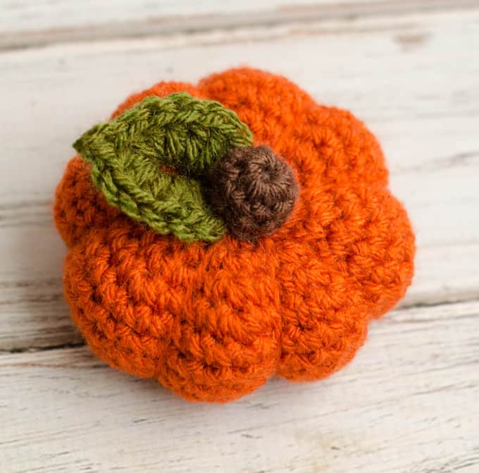 small orange crochet pumpkin with brown stem and green leaf