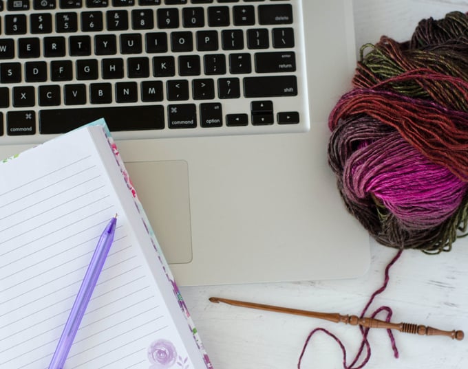 yarn and notebook on open laptop