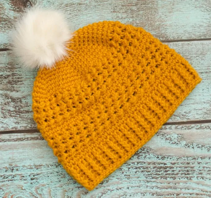 Yellow crochet hat with white fur pom pom