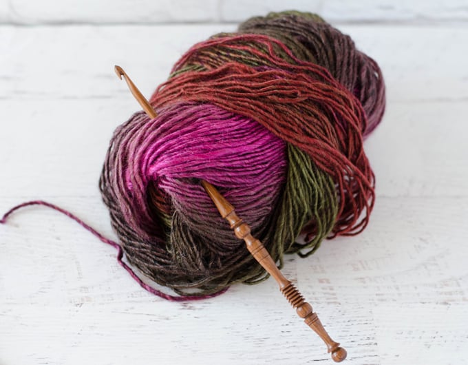 pink, red and green variegated yarn with brown wood hook