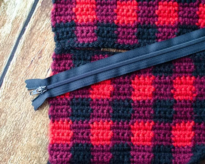 Assembling The Wristlet: Take the two side pieces and carefully sew in about ½” from each side, using black yarn. I used a mattress stitch for this, but you could use a different seaming method. Fasten off ends and weave them in. Now you have an open area in the middle. This is where the zipper is attached.