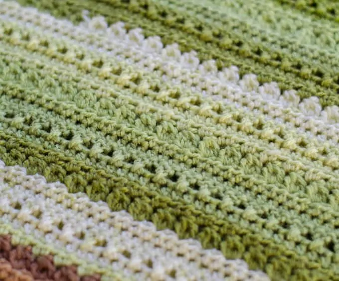 Close up of green, brown and cream Crochet afghan pattern