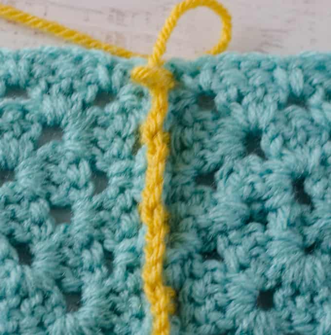 wrong side of Crochet Faux Braid Join in yellow yarn worked on blue granny squares