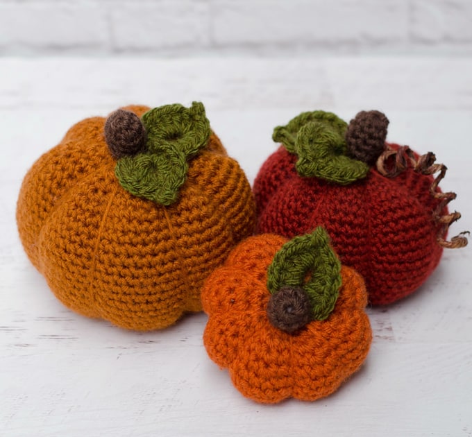 three crochet pumpkins in small, medium and large in different shades of orange yarn