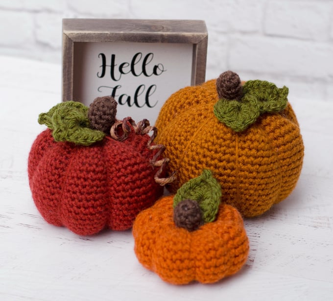 three orange crochet pumpkins with hello fall sign