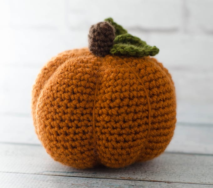 large crochet pumpkin in orange with green leaves and brown stem