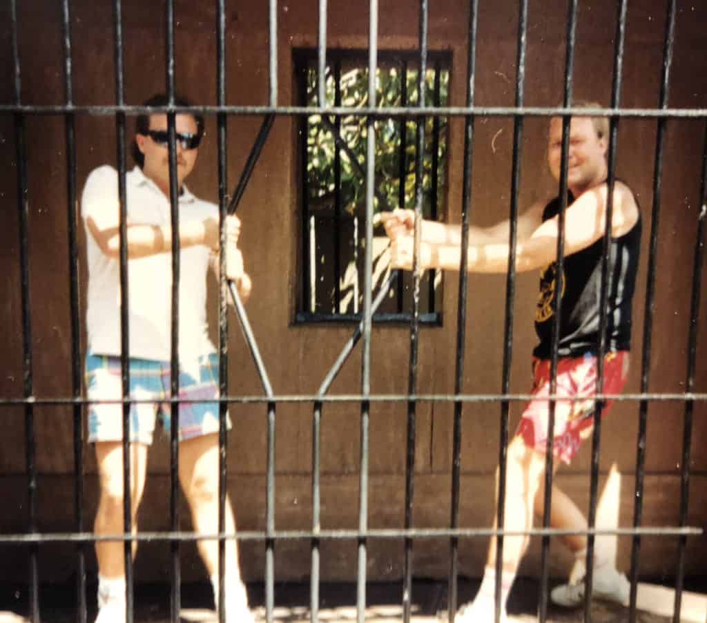 Two men in shorts pulling on jail cell bars