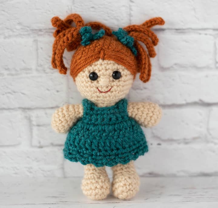 standing crochet doll with rust color hair and teal dress