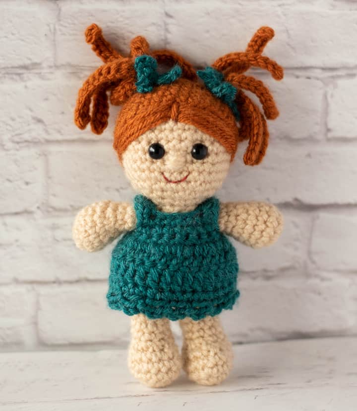 standing crochet doll with rust color hair and teal dress