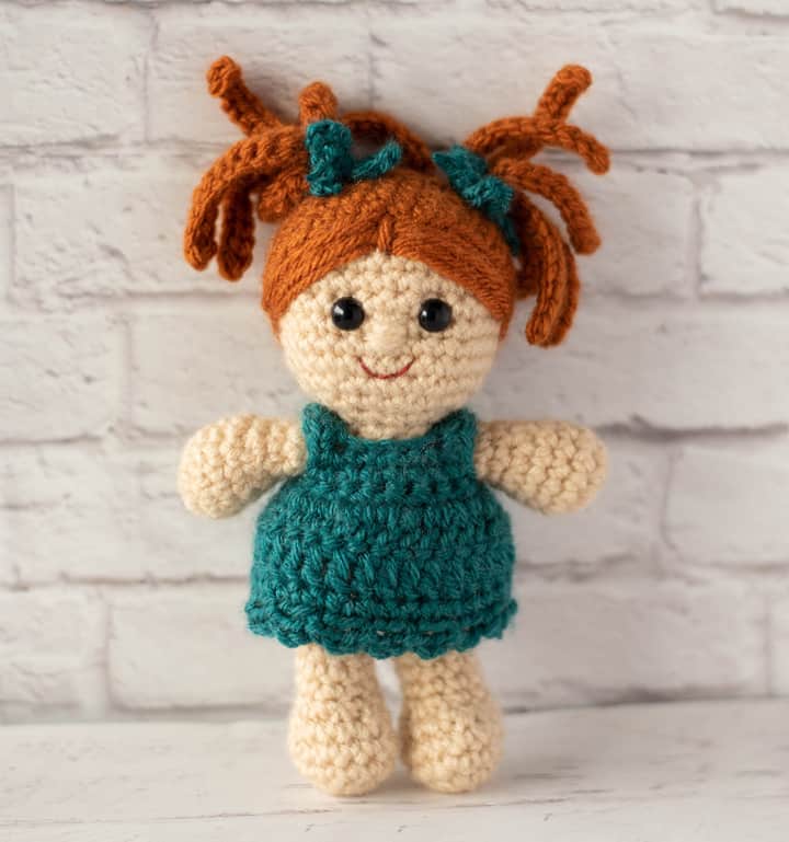 Standing crochet doll with rust color hair and teal dress