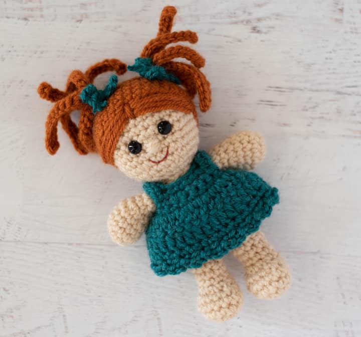 crochet doll with rust color hair and teal dress