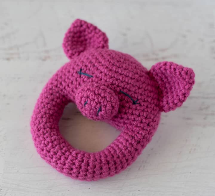 A pink crochet pig rattle on an angle