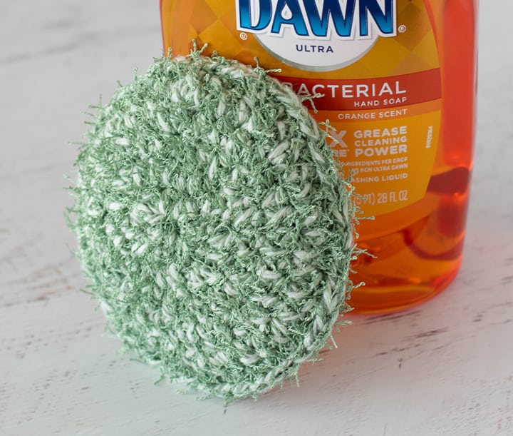 green crochet dish scrubber with dish soap