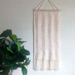 ivory crochet wall hanging next to plant