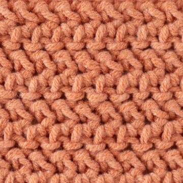 close up view of herringbone half double crochet stitch in salmon color yarn