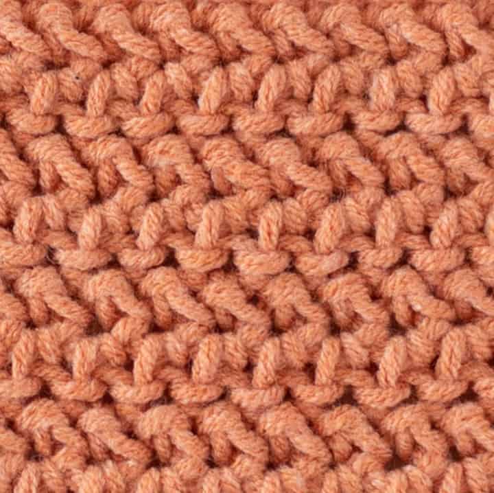 close up view of herringbone half double crochet stitch in salmon color yarn