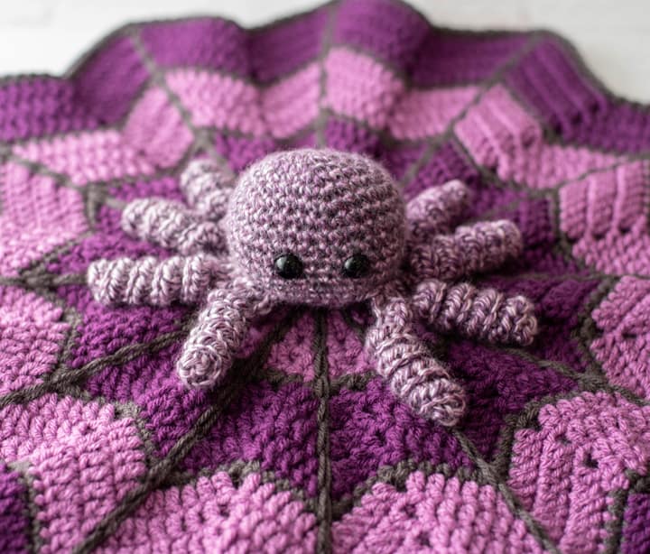 crochet spider on a light and dark purple crochet lovey blanket