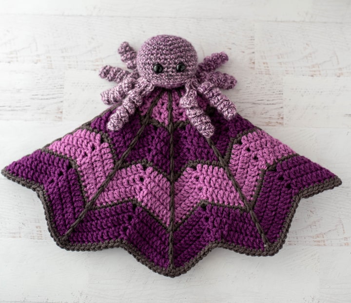 crochet spider on a light and dark purple crochet lovey blanket