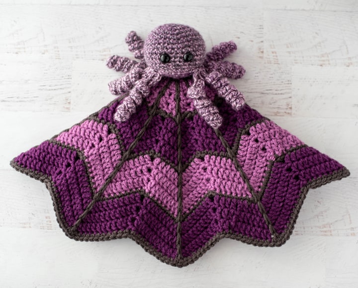crochet spider on a light and dark purple crochet lovey blanket