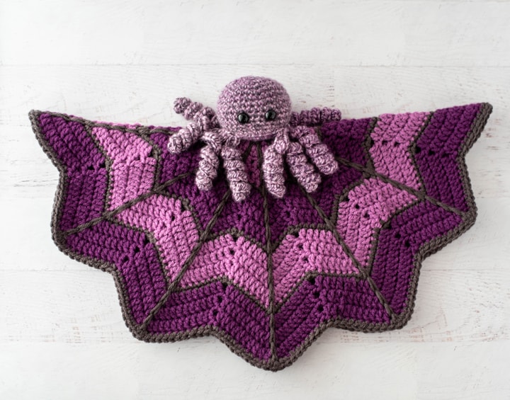 crochet spider on a light and dark purple crochet lovey blanket