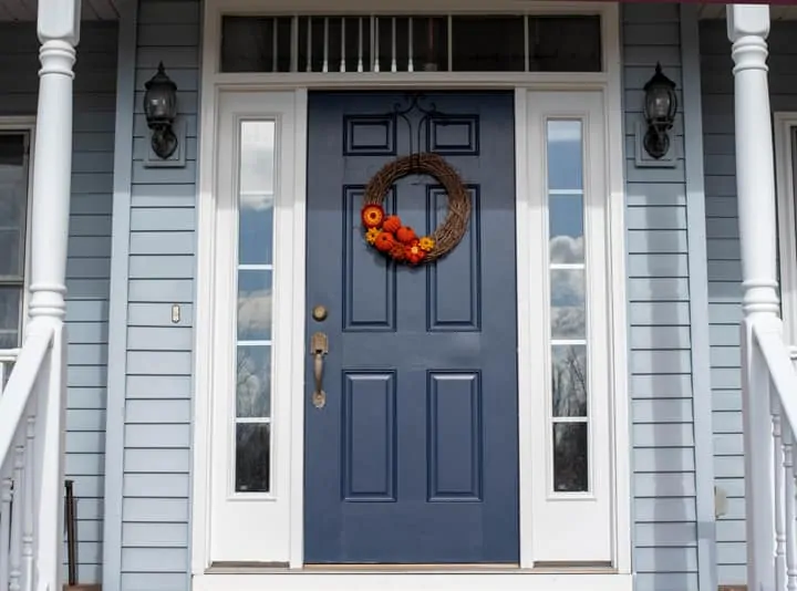 Grapevine wreath with crochet pumpkins and flowers on a blue door on a porch