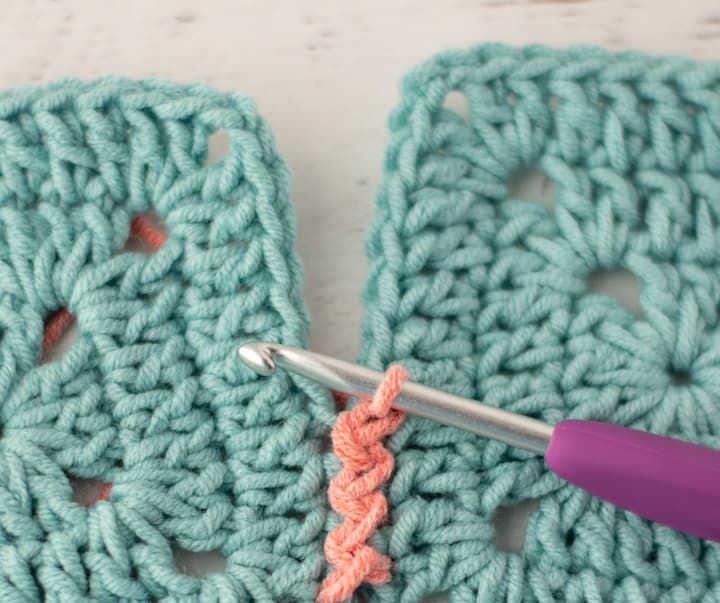 blue crochet granny squares with pink zig zag slip stitch join